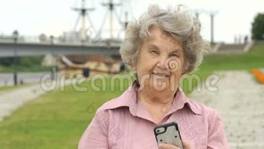 微笑成熟的老女人展示银色智能手机